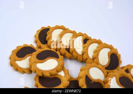 Biscotto di sicurezza sotto forma di sole con stucco bianco e cioccolato, dolce sotto forma di due gocce poste su fondo bianco. Foto Stock