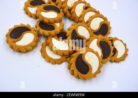 Biscotto di sicurezza sotto forma di sole con stucco bianco e cioccolato, dolce sotto forma di due gocce poste su fondo bianco. Foto Stock