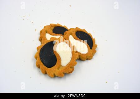 Biscotto di sicurezza sotto forma di sole con stucco bianco e cioccolato, dolce sotto forma di due gocce poste su fondo bianco. Foto Stock