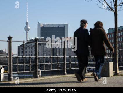 Berlino, Germania. 03 marzo 2021. Due persone camminano sulla riva del fiume Sprea nel quartiere governativo. La torre della televisione di Berlino può essere vista sullo sfondo. Credit: Kira Hofmann/dpa-Zentralbild/dpa/Alamy Live News Foto Stock