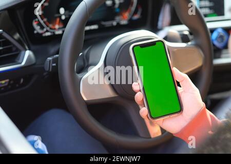 vista sulla spalla dello schermo verde intelligente che tiene la mano telefono in auto Foto Stock