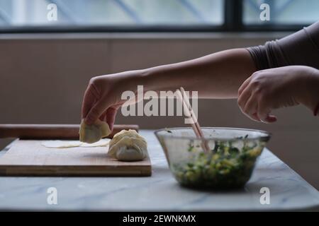 primo piano di fabbricazione manuale gnocchi. Cibo cinese tradizionale durante il nuovo anno cinese. Concetto di cultura cinese Foto Stock