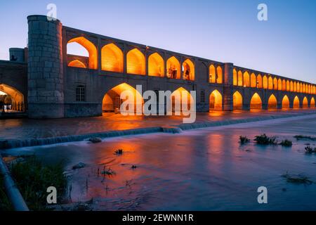 Isfahan, Iran - 14.04.2019: Nightfall al si o se Pol Bridge, Isfahan, Iran. Le luci arancioni sul ponte contrastano con il cielo blu sbiadimento. Foto Stock