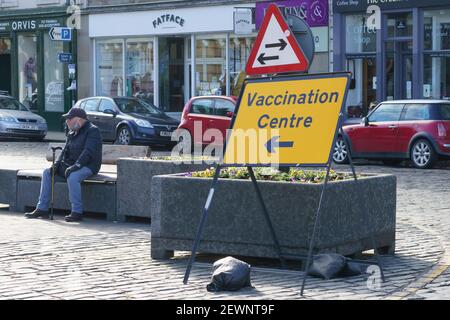 Accedi al centro di Kelso con negozi chiusi, uomo in maschera seduta sulla panchina, centro di vaccinazione Foto Stock