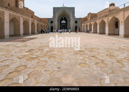 Yazd, Iran - 13.04.2019: Cortile della storica Moschea Jameh di Yazd con le sue piastrelle esagonali e turchesi. Persone che camminano nel cortile di Shia Foto Stock