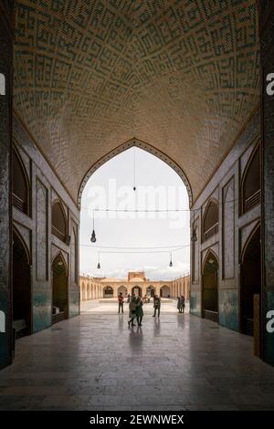 Yazd, Iran - 13.04.2019: Cortile della storica Moschea Jameh di Yazd con le sue piastrelle esagonali e turchesi. Persone che camminano nel cortile di Shia Foto Stock