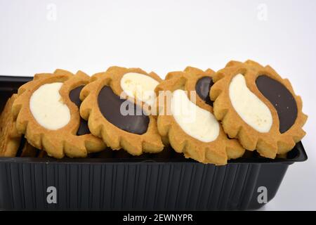 Deliziosi biscotti sabbiosi con bordi taglienti e cioccolato e riempitivo bianco investiti in confezioni marrone. Foto Stock