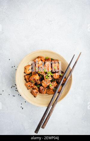 Cubetti di tofu fritti marinati in una ciotola di bambù. Pasto asiatico vegano sano Foto Stock