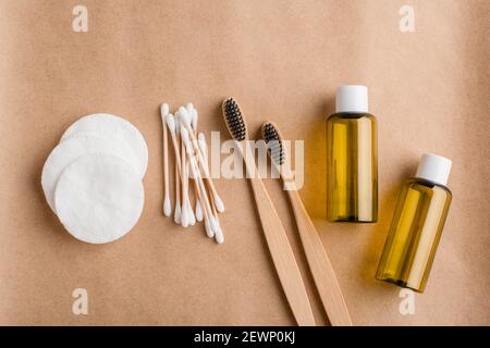 Accessori ecologici per la cosmetologia e la pulizia medica. Tamponi di cotone, bastoncini di bambù, pentole di essenza di olio e spazzolini da denti al carbone su dorso beige Foto Stock