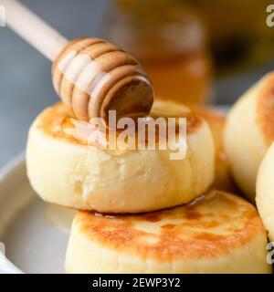 Frittelle di formaggio Syrniki, frittelle di formaggio dolce russo servite con miele. Vista in primo piano Foto Stock