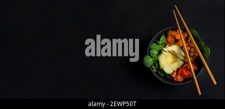 Ciotola di avocado vegano con pomodori ciliegini, spinaci e ceci. Vista dall'alto della ciotola di buddha. Concetto di cibo sano su sfondo scuro con spazio di copia. Foto Stock