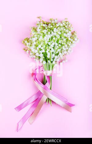 bouquet di giglio dei fiori di valle con nastri rosa primo piano su sfondo rosa Foto Stock