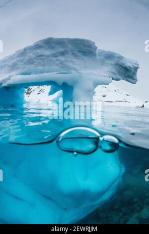 Vista sopra e sotto di un arco formato in un iceberg a Cuverville Island, canale di Ererra, Antartide, regioni polari Foto Stock