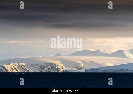 Alba su montagne innevate e ghiacciai alle acque tiedee nel porto di Mikkelsen, Trinity Island, Antartide, Polar Regions Foto Stock