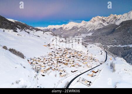 Strada di montagna che attraversa il villaggio di Ardez coperto di neve, vista aerea, Engadina, Cantone Graubunden, Svizzera, Europa Foto Stock