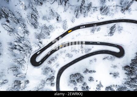 Vista aerea di auto che guidano su strette curve di strada di montagna nella neve, Svizzera, Europa Foto Stock