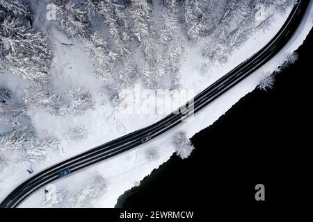 Automobili che guidano su strada ghiacciata attraverso boschi innevati ai margini del Lago di Sils, vista aerea, Engadina, Cantone di Graubunden, Svizzera, Europa Foto Stock