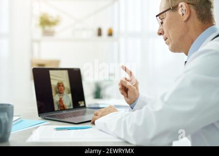 Medico maschile che dà consultazione online a una donna anziana in clinica Foto Stock