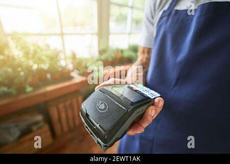 Terminale della banca nella mano del venditore maschio Foto Stock