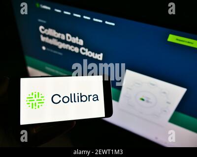 Persona che detiene il telefono cellulare con il logo aziendale della società di software belga Collibra NV sullo schermo davanti alla pagina web. Focus sul display del cellulare. Foto Stock