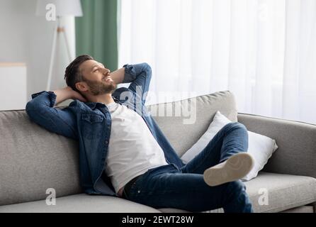 Uomo di mezza età rilassato che riposa sul divano a casa Foto Stock