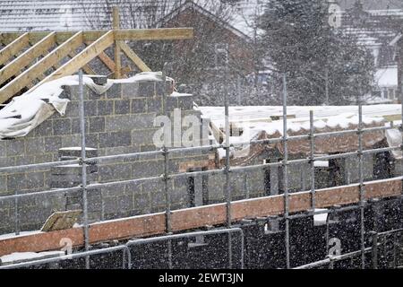 I lavori di costruzione interrompono il ghiaccio sul luogo di lavoro dei ponteggi non sicuro in condizioni di neve ghiacciata neve inverno cada tempo causando disturbo Inghilterra Regno Unito Foto Stock