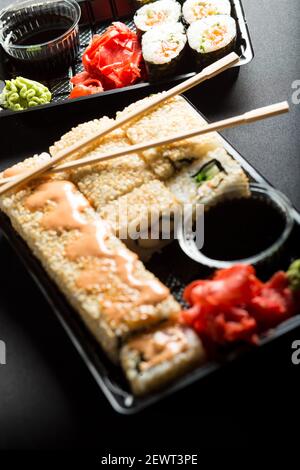 Set di sushi in contenitori di plastica, su sfondo nero, stile di vita. Foto Stock