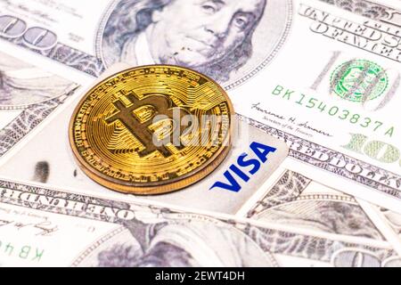 SLOVENIA, LUBIANA - 2 marzo 2021: Moneta di Bitcoin e carta di credito Visa sulle bollette del dollaro. Foto Stock