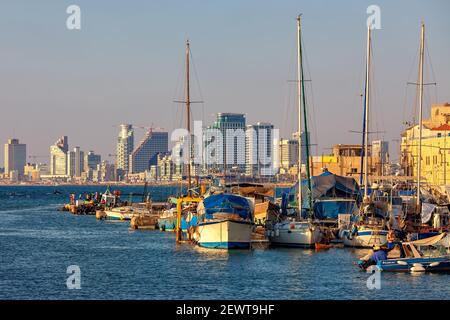 Barche e yacht ormeggiati nel vecchio porto di Jaffa come edifici moderni di Tel Aviv visto sullo sfondo. Foto Stock