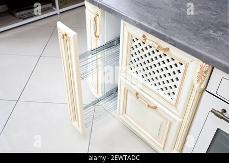 Estrarre il pannello di riempimento dell'armadietto portavetrini. Interni moderni in stile classico con elementi dorati in colori beige. Cassetto verticale per spezie Foto Stock