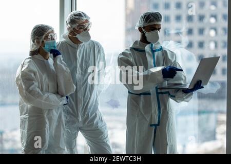 Medico scienziato in Hazmat SUIT che lavora computer portatile all'interno del laboratorio Ospedale - Focus sulla mano della donna Foto Stock