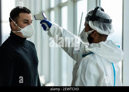 L'infermiere misura la temperatura corporea con un termometro a infrarossi  in africa di mezza età uomo americano Foto stock - Alamy