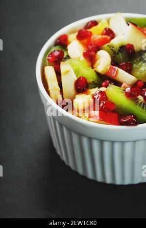 Tazza di Macedonia di frutta fresca fatta di frutta succosa su sfondo nero. Spazio libero per il testo. Fette di frutta fresca, succosa e sana per una dieta sana. Foto Stock