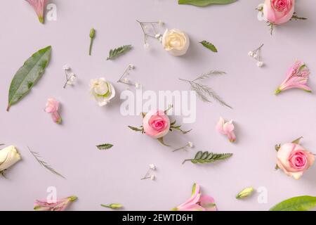 Primavera fiori sfondo. Rose, flora rosa e foglie casualmente su sfondo grigio. Concetto di posa piatta, estetica pastello Foto Stock
