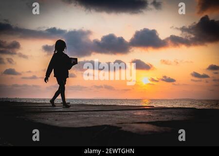 Una giovane cambogiana cammina a casa dopo una lunga giornata lavoro di vendita di trinket a vari viaggiatori sulla sua piccola isola Foto Stock