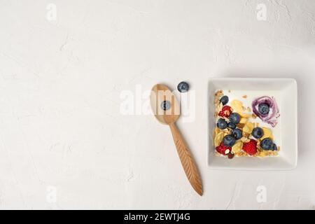 Sana colazione ciotola, cornflakes, yogurt e frutti di bosco freschi su una lavagna. Close-up, vista dall'alto, isolato sfondo. Concetto di sana e gustosa Foto Stock