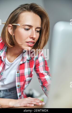 Giovane donna concentrata fissando lo schermo del computer Foto Stock