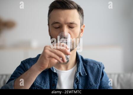 Primo piano di un uomo di mezza età che beve acqua a casa Foto Stock