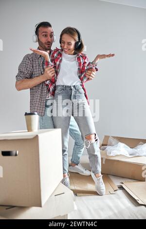 Coppia in piedi tra scatole di cartone sparse nella stanza non arredata Foto Stock