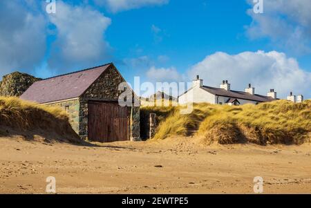 La casa di Lifeboat e tetti dei cottage del pilota bianco dalla spiaggia sull'isola di Llanddwyn, Anglesey, Galles Foto Stock