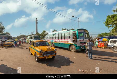 Taxi giallo con autobus di trasporto pubblico al terminal degli autobus della città Con vista sullo storico Shaheed Minar a Kolkata India Foto Stock