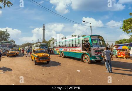 Taxi giallo con autobus di trasporto pubblico al terminal degli autobus della città Con vista sullo storico Shaheed Minar a Kolkata India Foto Stock