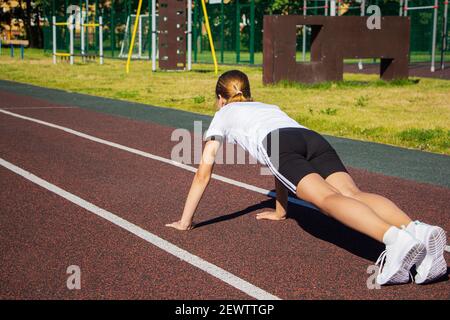Una ragazza adolescente fa push-UPS sul parco giochi. Fitness, sport, salute Foto Stock