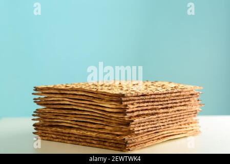 Matzah su tavolo bianco su sfondo blu. Matza - pane azzimo tradizionale ebraico Passover. Simbolo della celebrazione di Pesach. Foto Stock