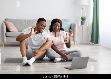 Felice coppia nera che dice addio al allenatore di yoga dopo la lezione Foto Stock