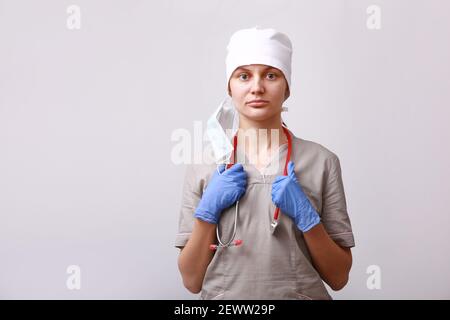 Ritratto di dottore in uniforme medica e maschera rimossa dal viso. Stetoscopio sul collo. Su fondo bianco. Sanità e Medicina. Di Foto Stock