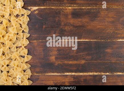 Vista dall'alto della pasta di farfalle su un tavolo di legno con spazio per la copia. Foto Stock