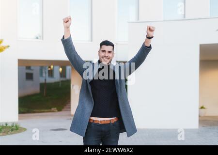 Giovane uomo d'affari con le braccia sollevate in vittoria. Foto Stock