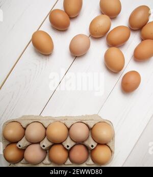 cassetta riempita con uova di pollo fresche e vicino a molti uova su tavola bianca Foto Stock