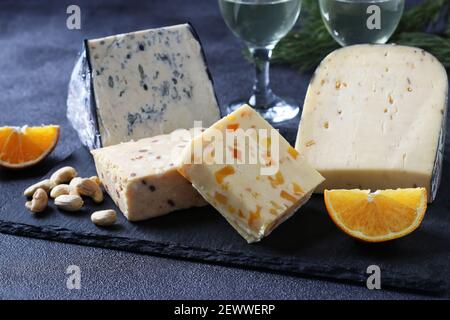 Assortimento di formaggi d'elite su una tavola d'ardesia su sfondo scuro. Spuntini per una festa del vino. Foto Stock